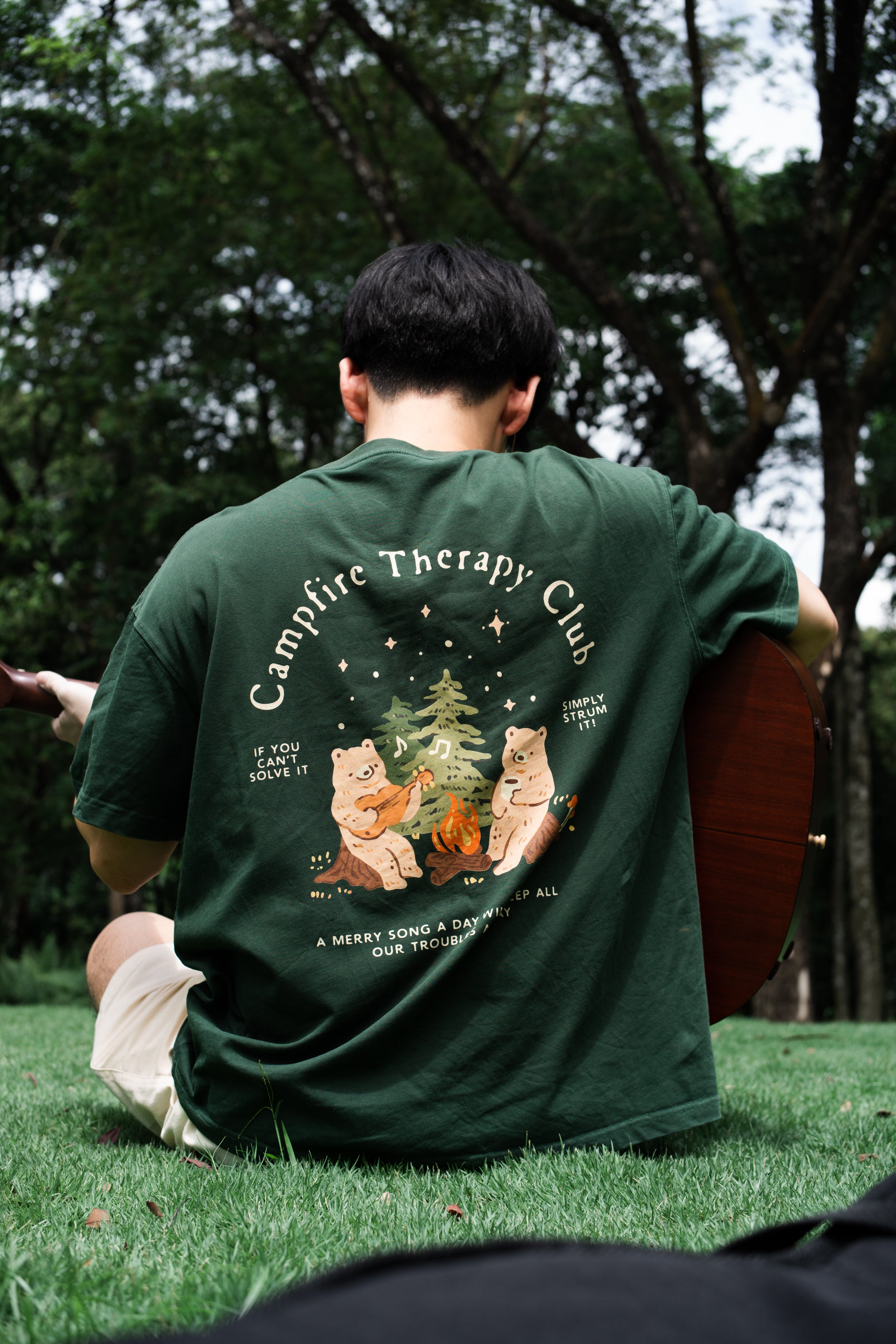 Person wearing a green t-shirt with bear graphics and text in an outdoor setting